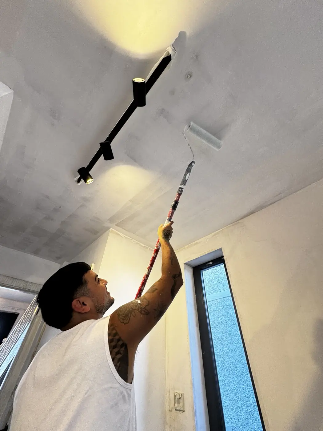 Painter applying a fresh coat to an interior ceiling in a Dublin home