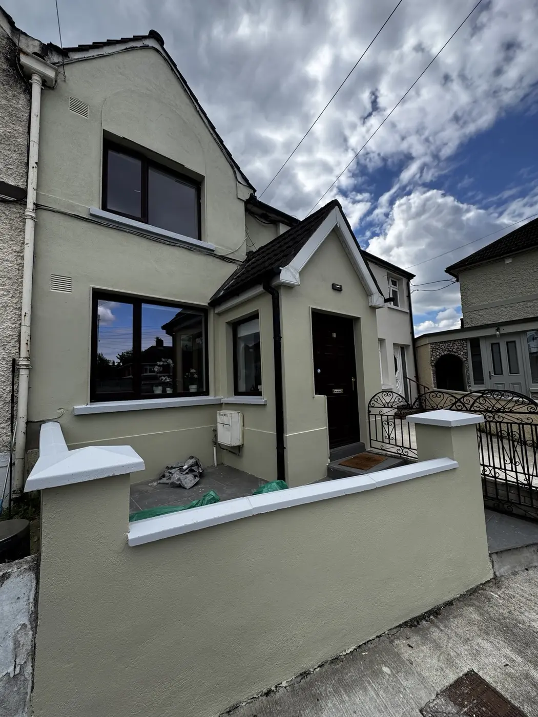 Completed exterior house painting project in Dublin with soft green walls and white details