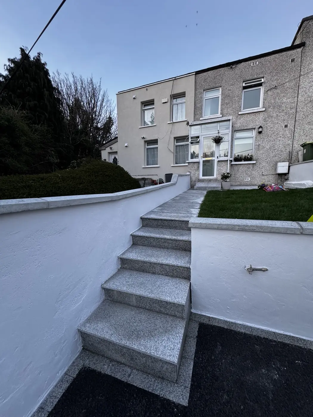 Completed white garden wall painting beside exterior steps in Dublin